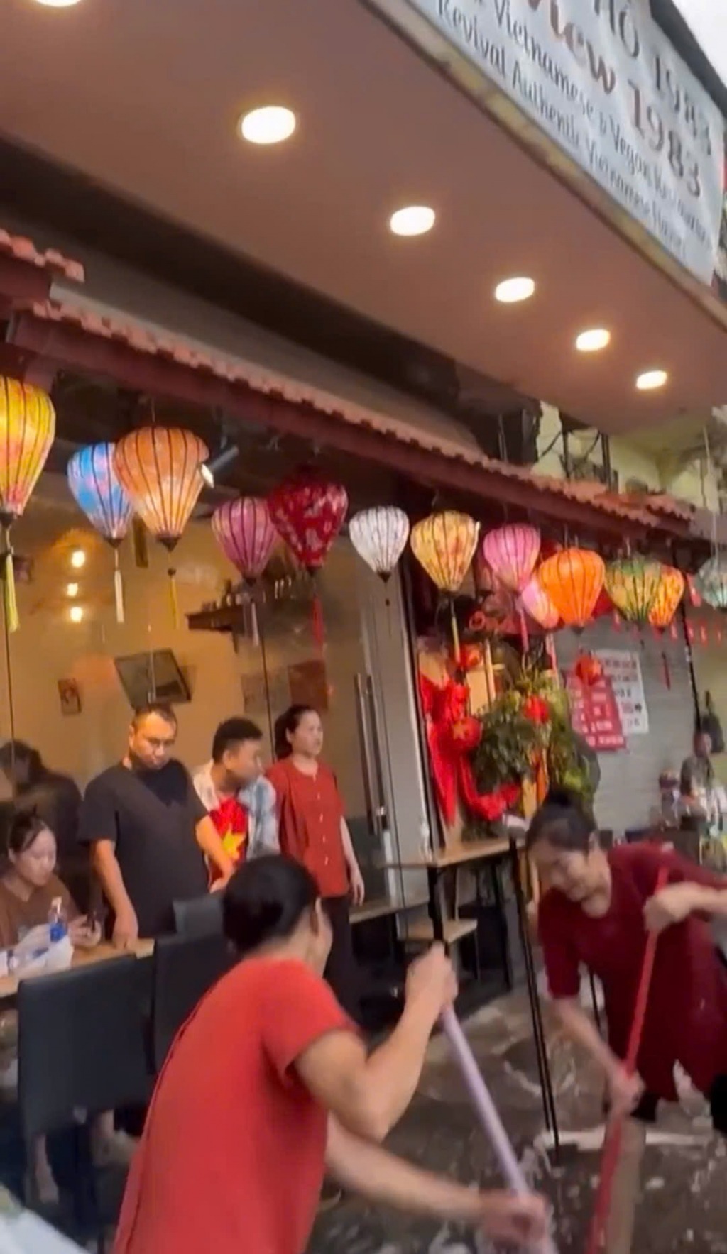 Nhân viên cửa hàng đã đổ nước để dọn rửa tại thời điểm có một số người dân trải nilon ngồi tại vỉa hè trước cửa hàng chờ xem diễu binh.