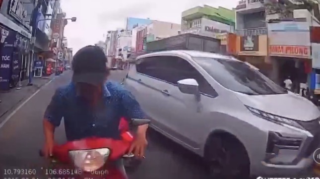 Một t&agrave;i xế xe m&aacute;y giống người đ&agrave;n &ocirc;ng tr&ecirc;n c&oacute; h&agrave;nh vi li&ecirc;n tục h&uacute;c v&agrave;o đu&ocirc;i một &ocirc; t&ocirc; đang chạy tr&ecirc;n đường
