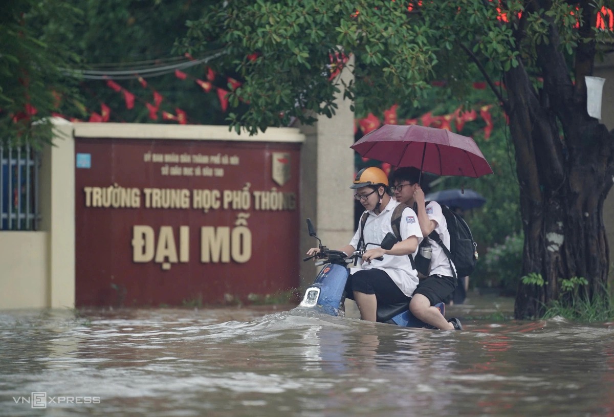 Học sinh tan trường trong cơn mưa lớn. Ảnh: VnE